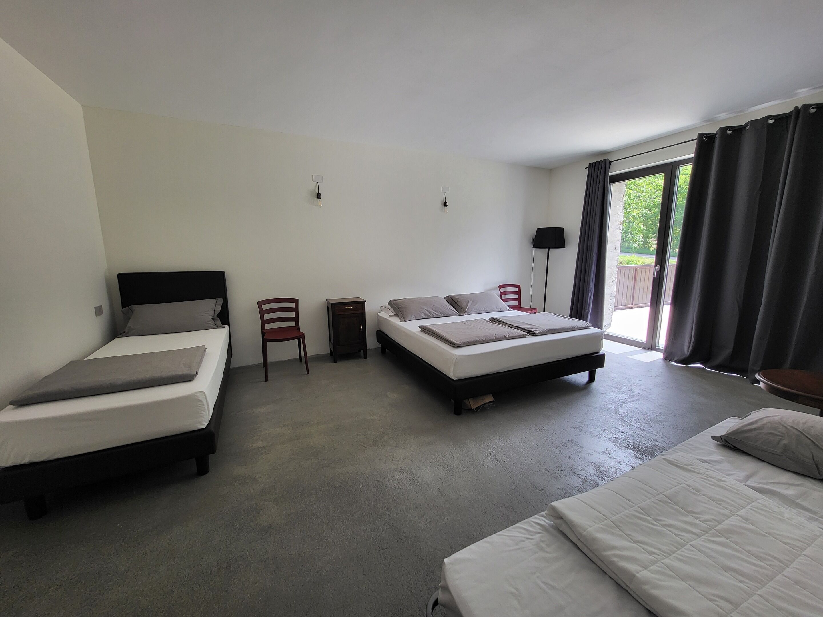 A hotel room with two beds, a chair, a nightstand, and a window with curtains.