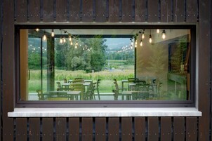 Comedor con vista a un campo cubierto de hierba y árboles a través de un ventanal grande.