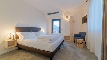 Une chambre d’hôtel moderne avec un grand lit, des tables de chevet, une chaise et une vue sur la ville.