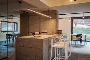 Una cocina moderna con una isla central, taburetes de bar y una botella de vino.