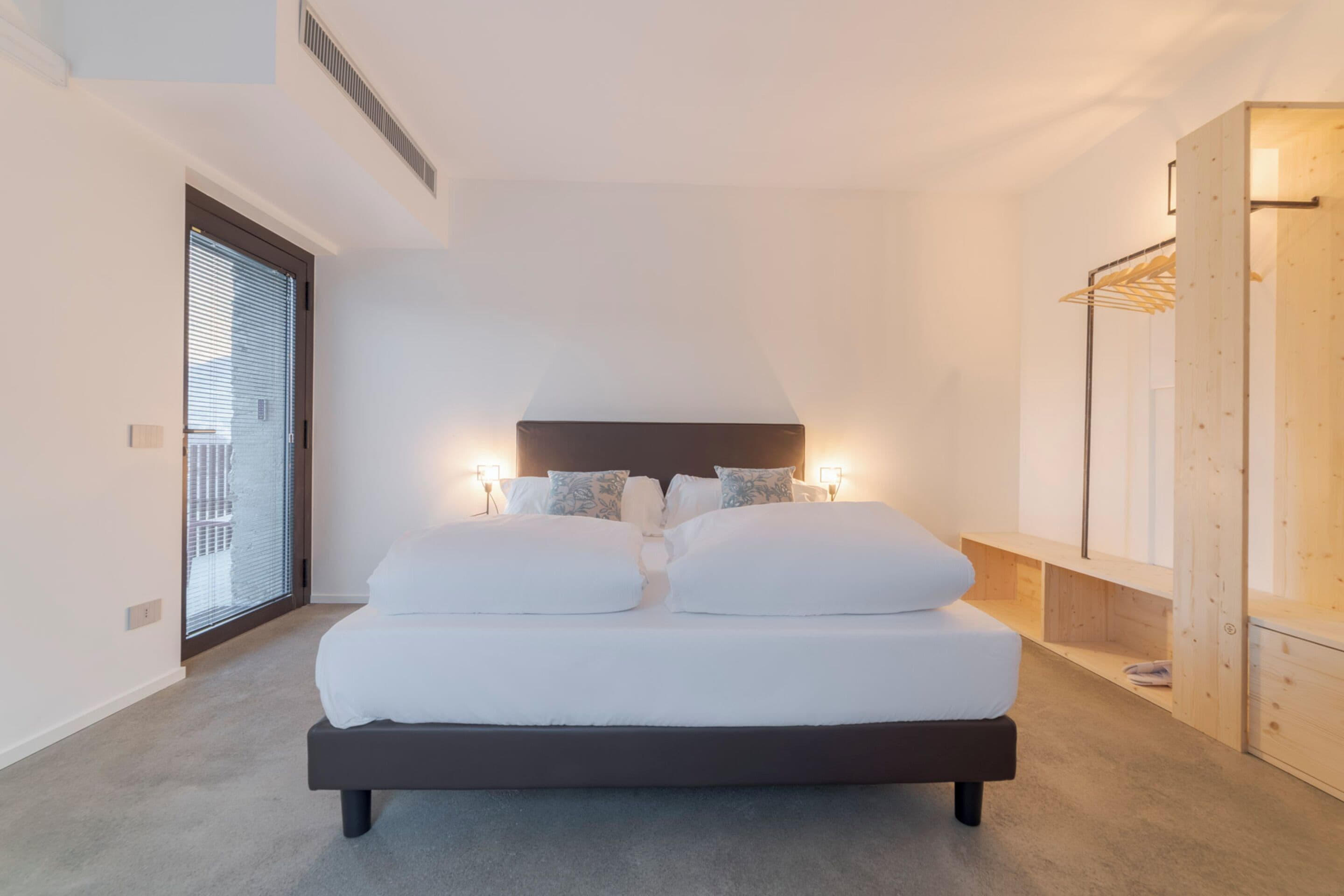 Una camera da letto moderna con un letto grande, lampade ai comodini e un armadio in legno.