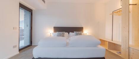 Un dormitorio moderno con una cama grande, lámparas de noche y un armario de madera.