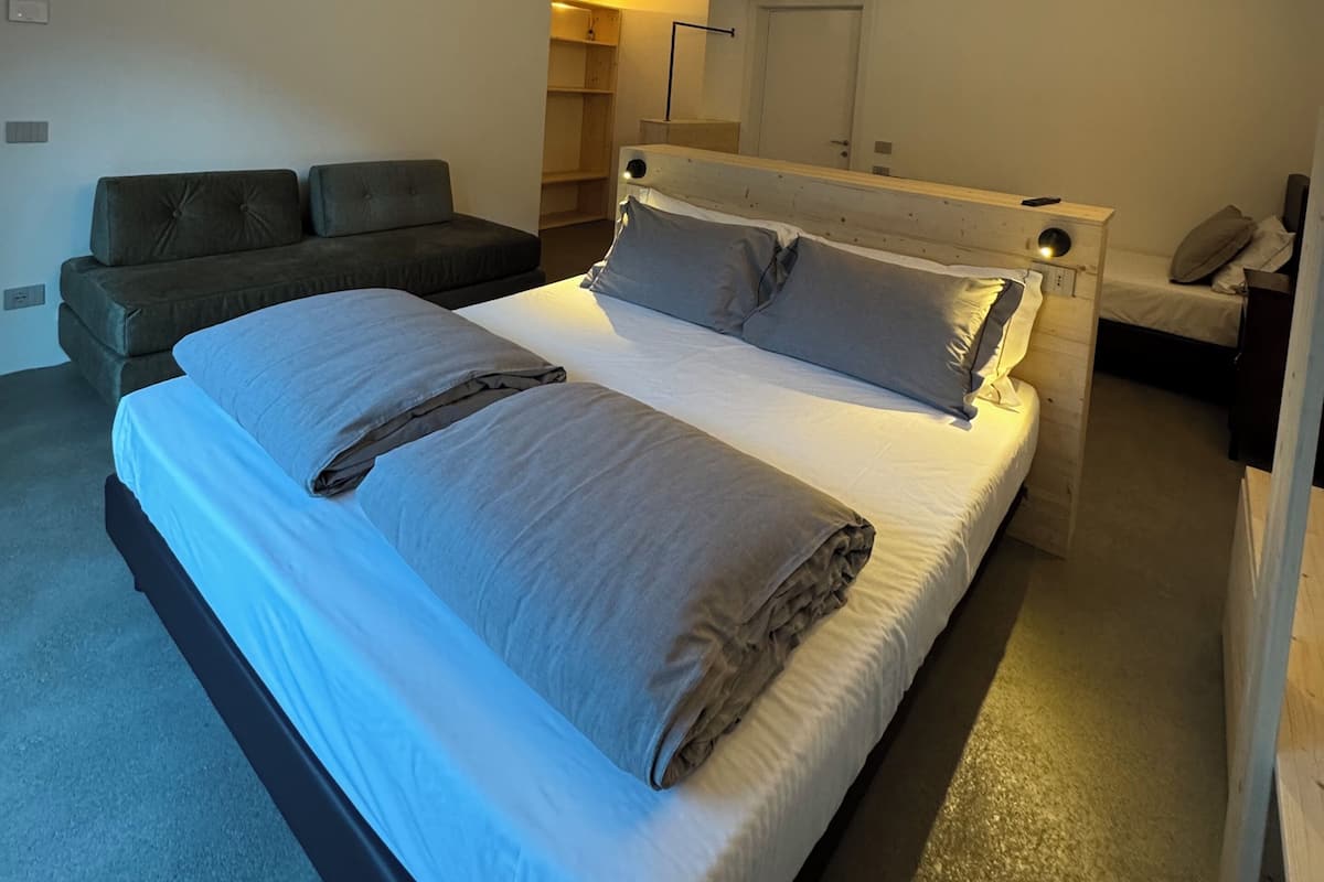 Un dormitorio con una cama grande, un sofá, una mesita de noche y un equipo de aire acondicionado.
