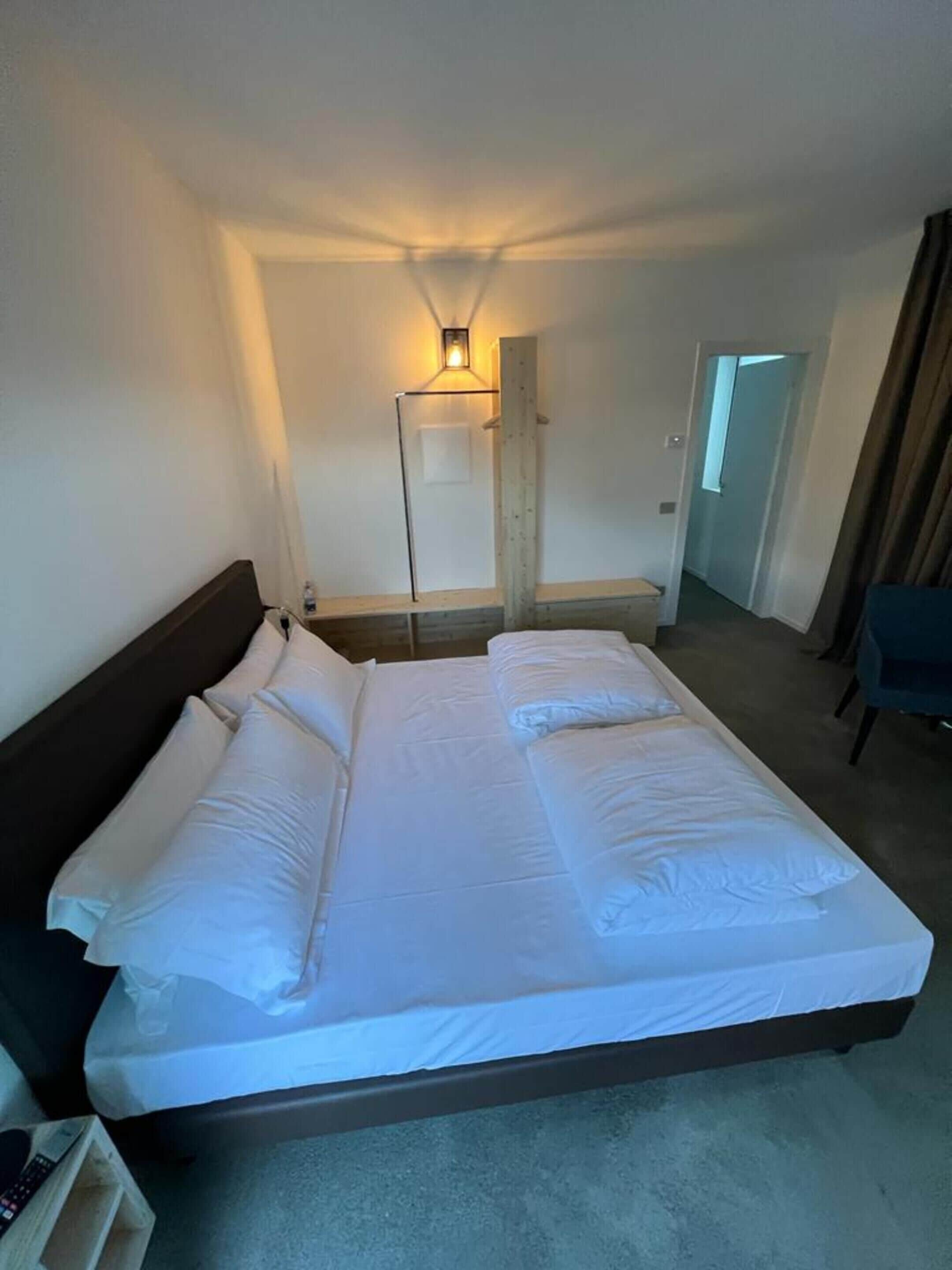 Une chambre d’hôtel avec un grand lit, une table de chevet, une lampe et un miroir.
