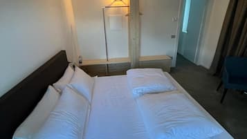 Une chambre d’hôtel avec un grand lit, une table de chevet, une lampe et un miroir.