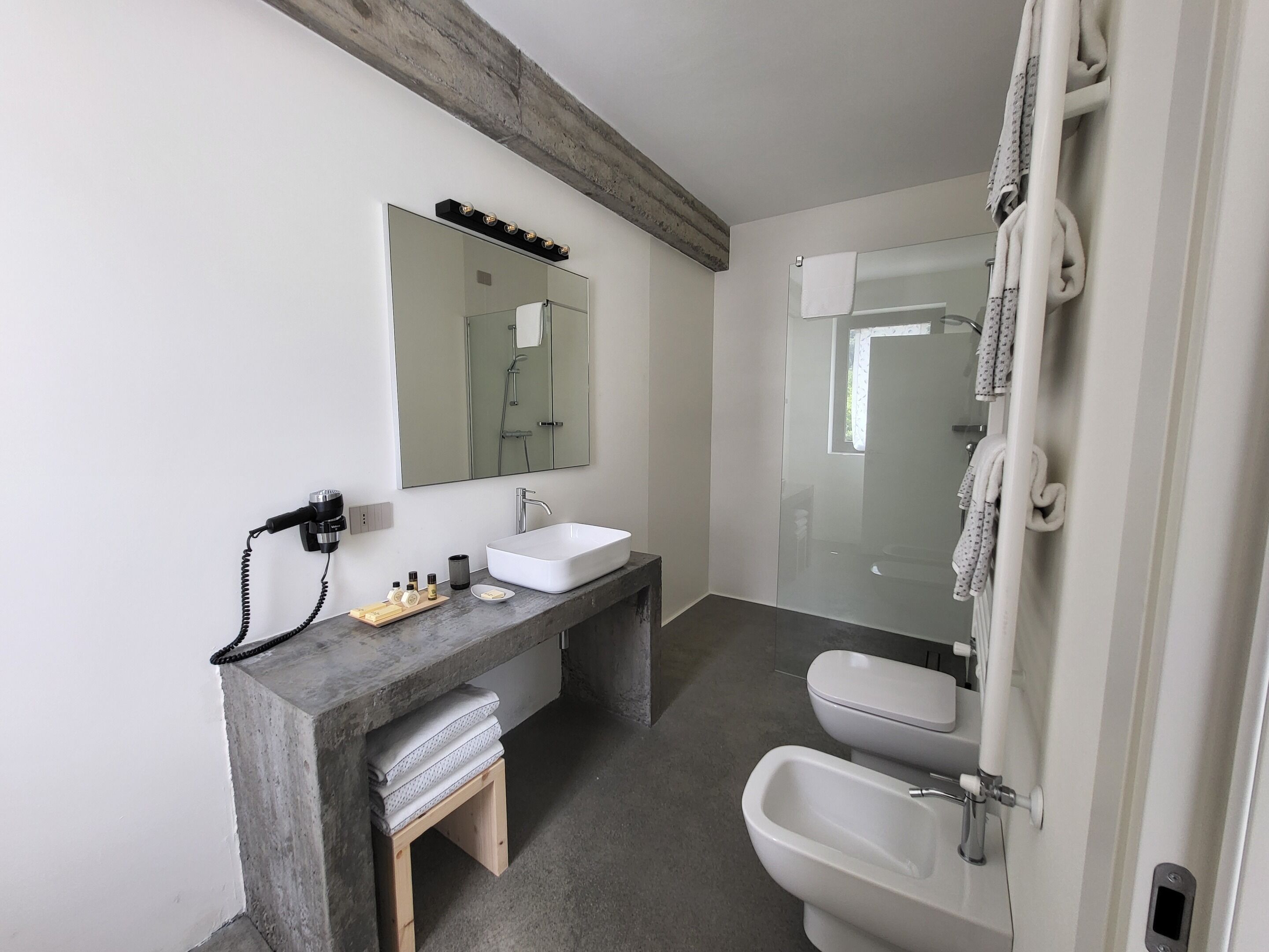 Une salle de bain moderne avec un grand miroir, un lavabo blanc, un bidet et un espace douche.