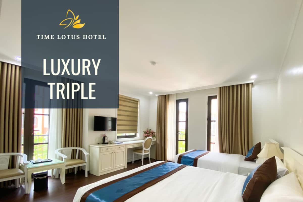 Habitació triple de luxe a l'Hotel Time Lotus, amb llit, escriptori, cadira i televisió.