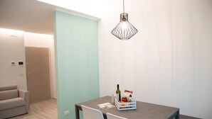 Un espace de salle à manger moderne avec une table, des chaises, un luminaire suspendu et une porte en arrière-plan.