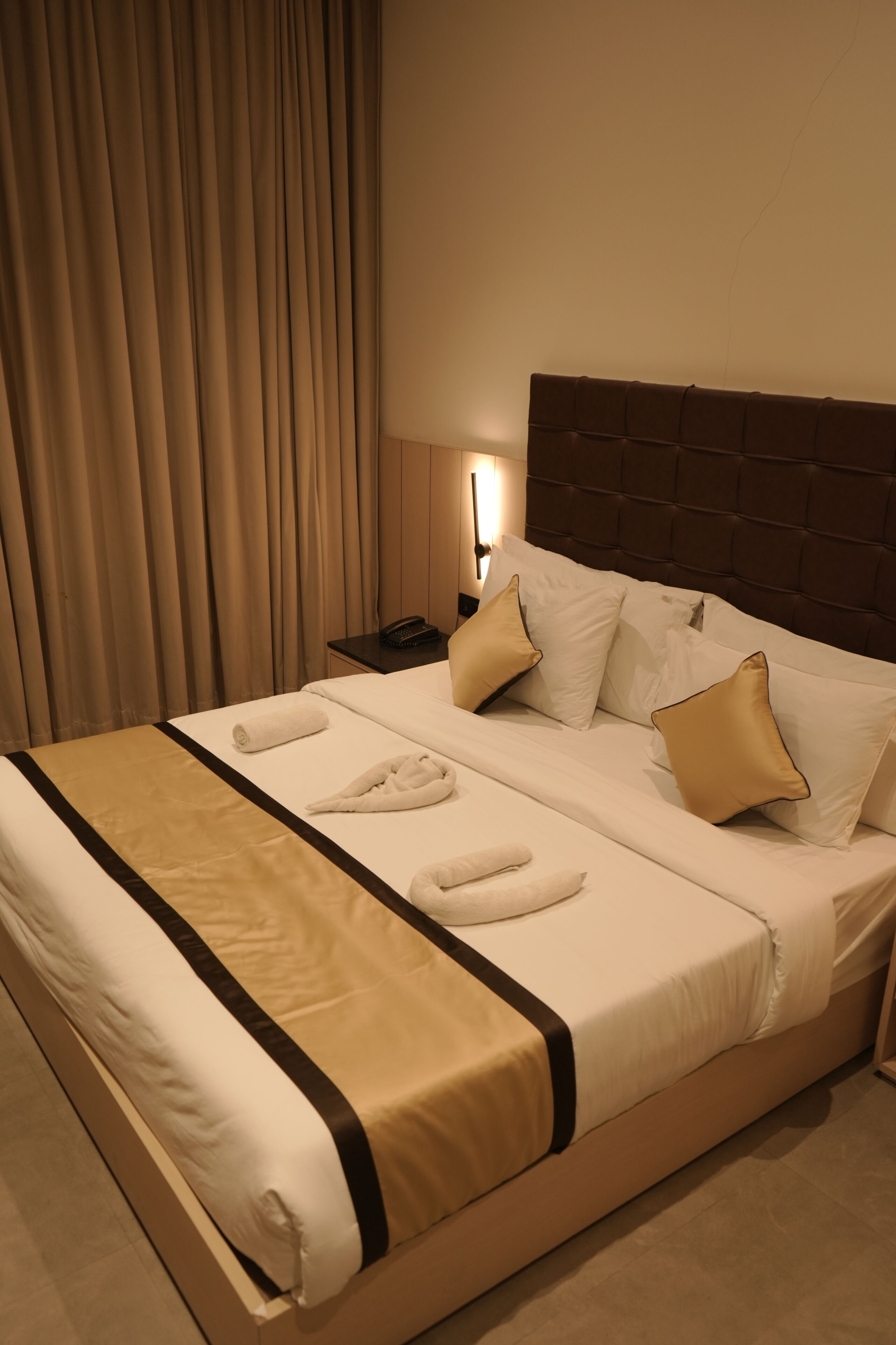A neatly made bed with a headboard, pillows, and a blanket.