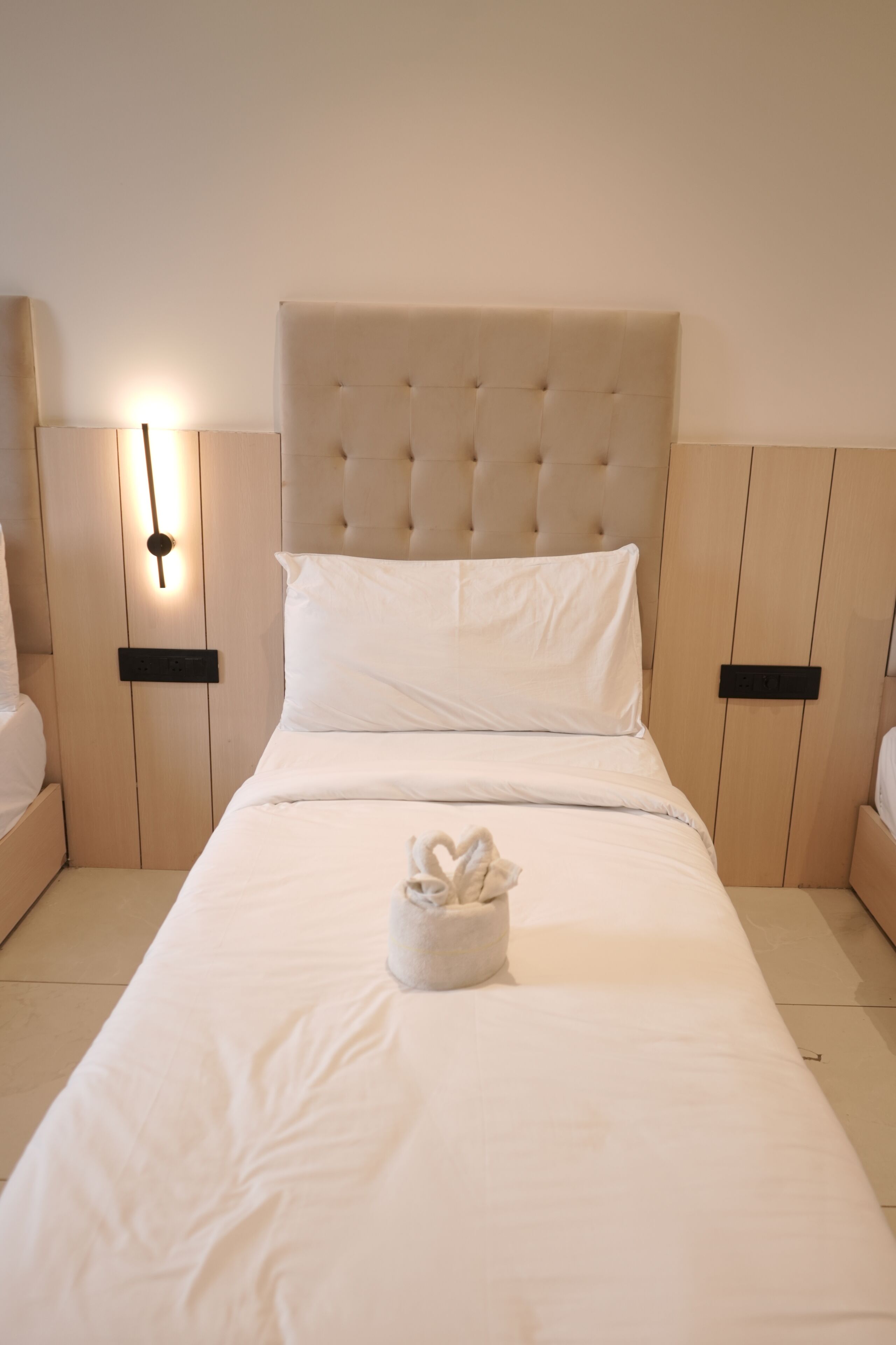 A neatly made bed with a tufted headboard, white linens, and a small white decorative item on the bed.