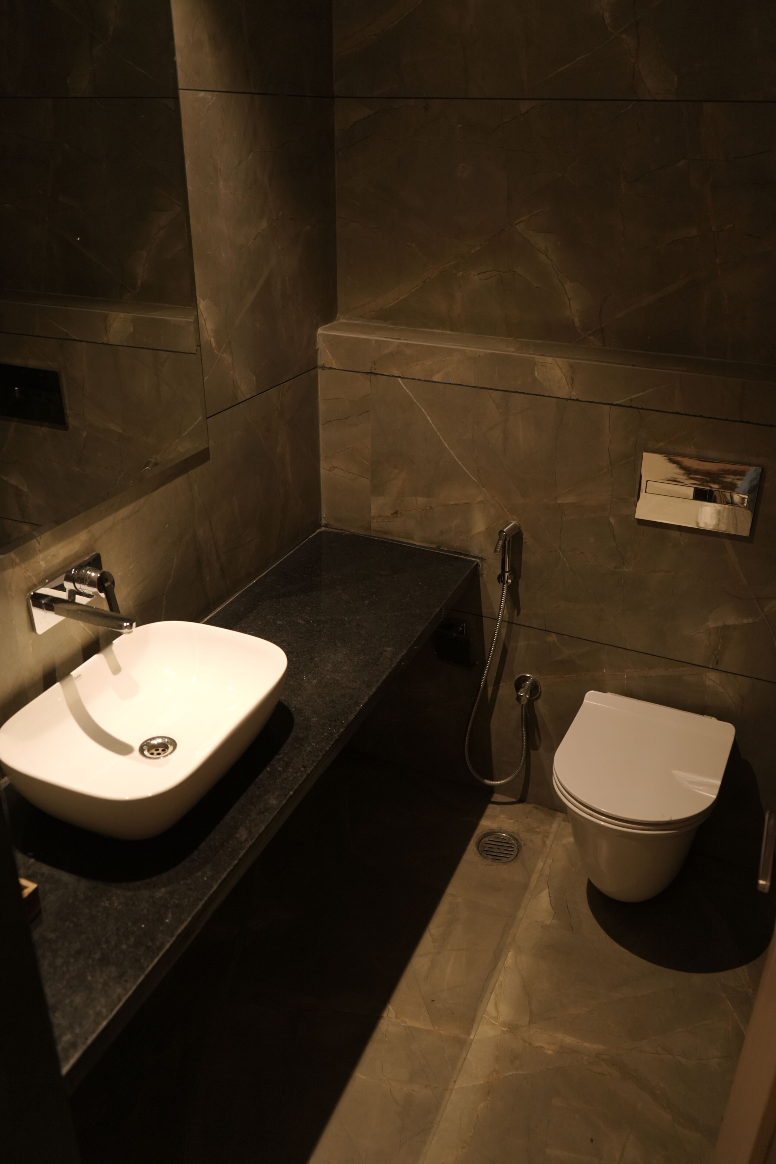 A modern bathroom with a marble sink, a toilet, and a shower.