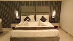 Un lit bien fait, avec une tête de lit, deux tables de chevet et un mur orné de rayures verticales.