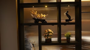 Une étagère noire sur laquelle sont disposés divers objets décoratifs, notamment des fleurs, une sculpture et une figurine de taureau aux couleurs vives.