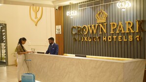 Un comptoir d’accueil à l’entrée des hôtels de luxe Crown Park, doté d’un design moderne, du logo de la couronne et d’un panneau indiquant les heures d’enregistrement.