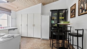 Una cocina con armarios blancos, una estufa, un refrigerador y un comedor con taburetes negros y una mesa.