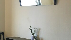 A room with a built-in shelf, two chairs, and a mirror on the wall.