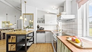 Una cocina moderna con armarios blancos, encimera de madera y lavavajillas integrado.