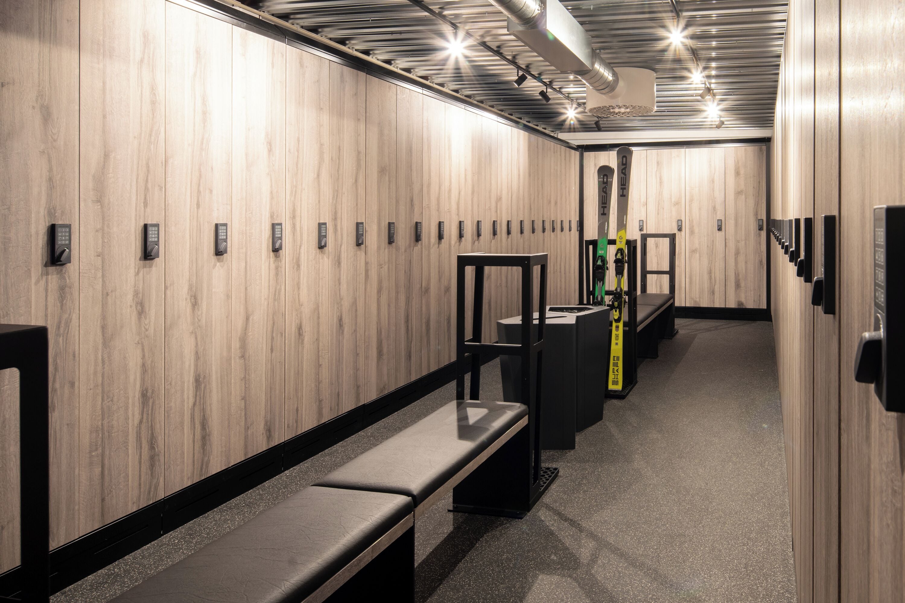 A modern bathroom with wooden paneling, multiple benches, and a ski rack.