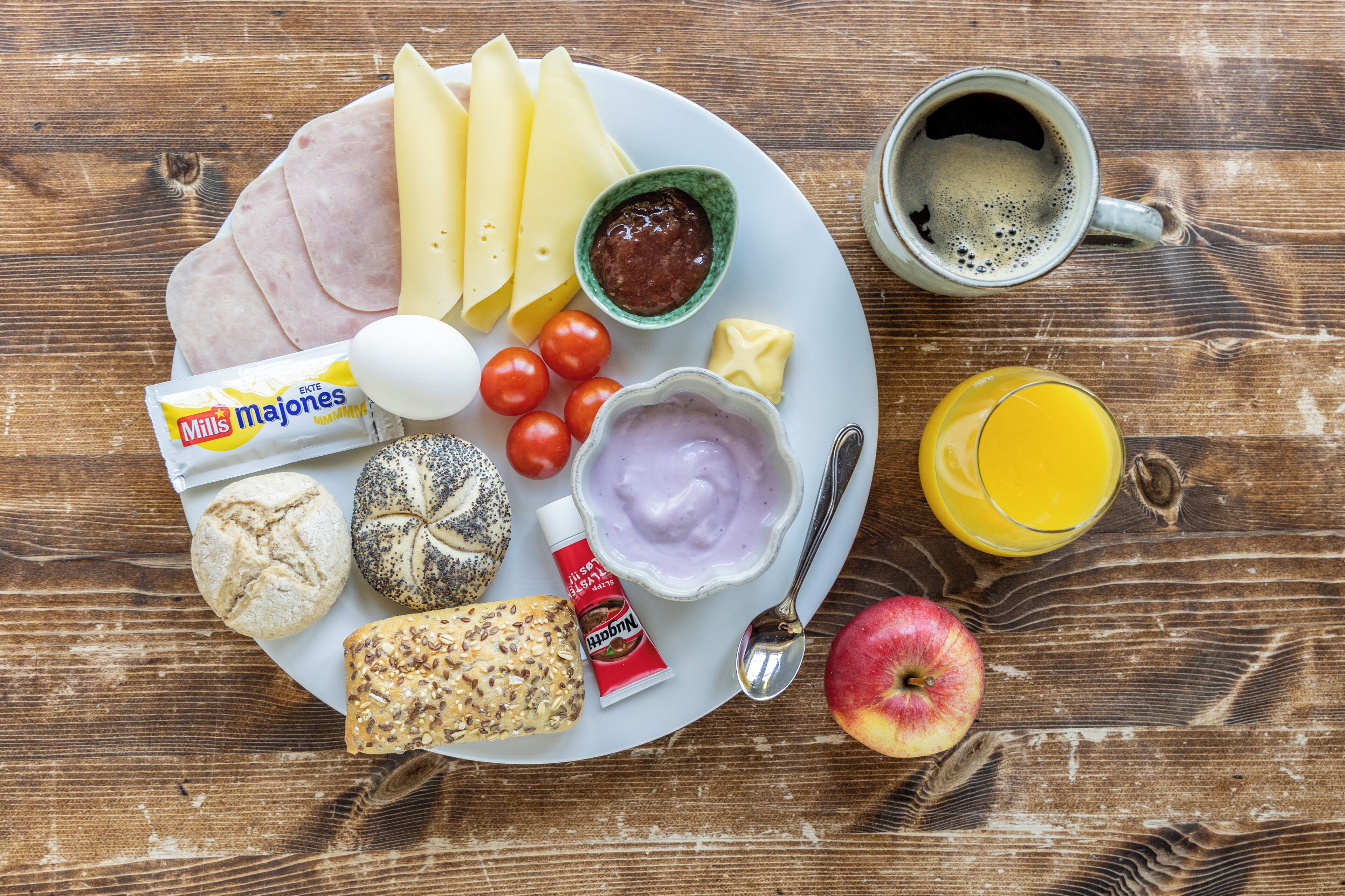 A breakfast plate with ham, cheese, eggs, bread, tomatoes, and a cup of coffee.