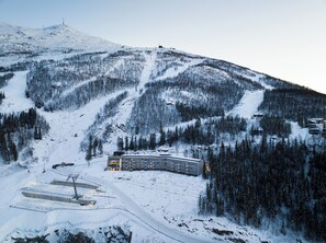 A snow-covered mountain with a ski resort building featuring a large glass facade and a ski lift in the background. - Basecamp Narvik (Narvik)