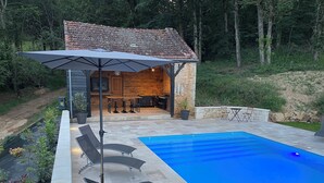 Une piscine avec des chaises longues et un espace cuisine extérieur.