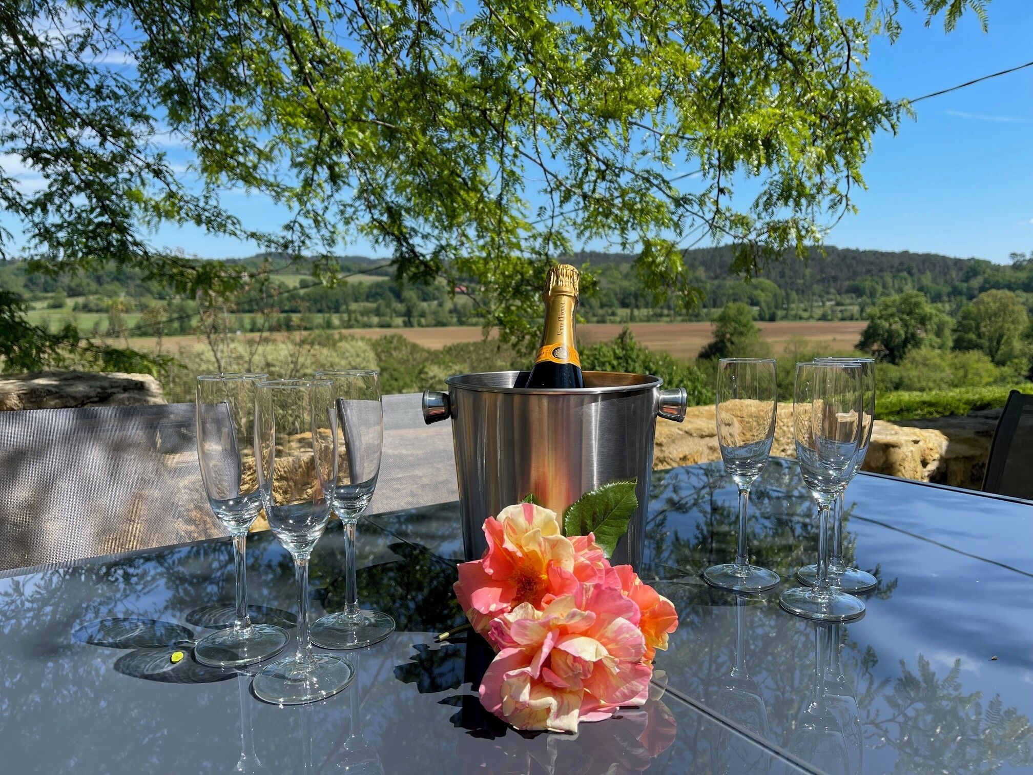 Une table avec une bouteille de champagne, des verres et une fleur.