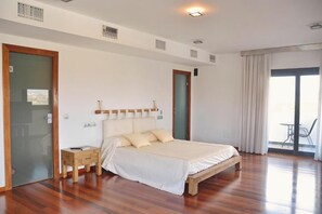 Relax in a spacious room with a large bed, two bedside tables, and a sliding door leading to an outdoor area.