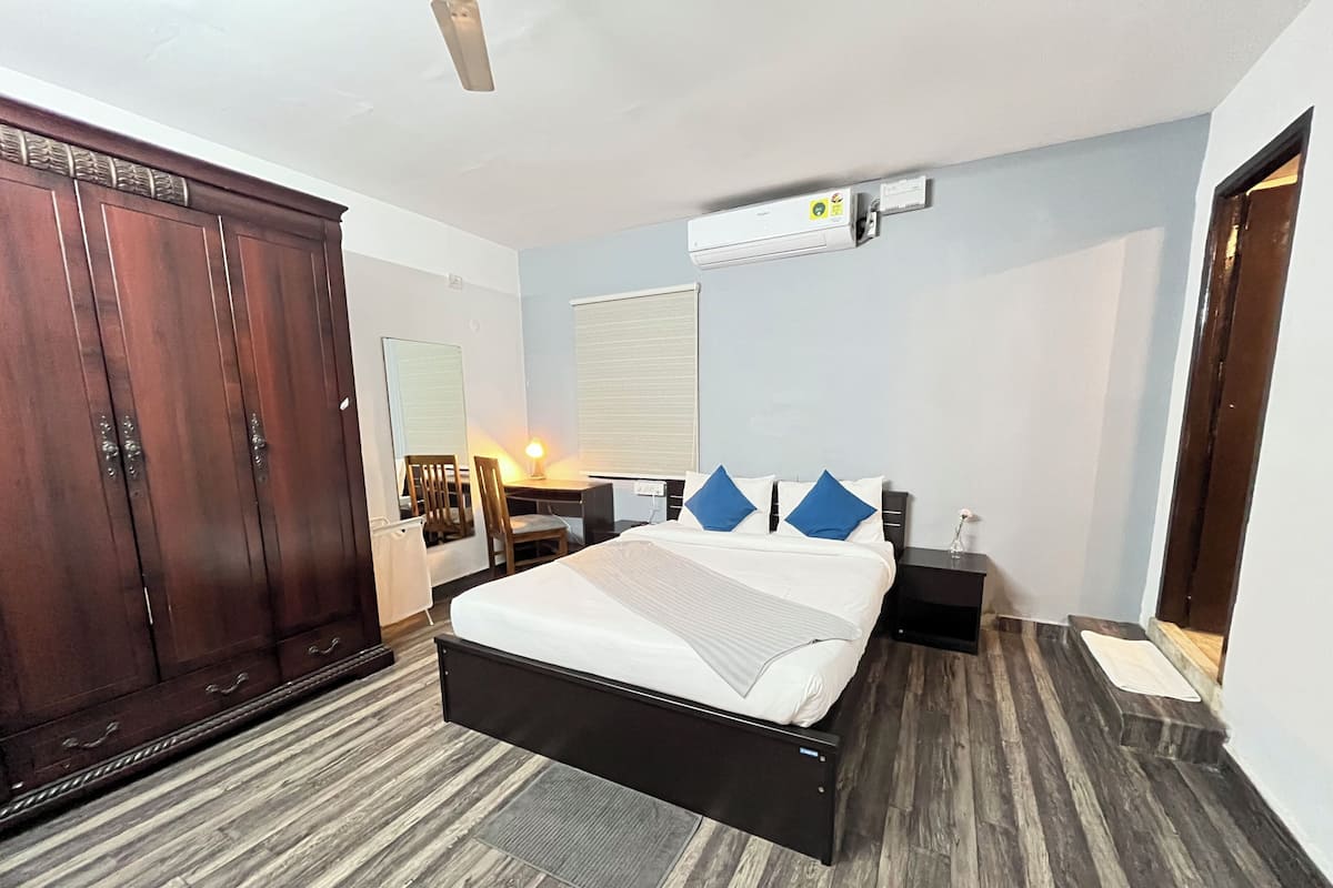 Ein Hotelzimmer mit einem großen Bett, einem Kleiderschrank, einem Schreibtisch und einer Klimaanlage.