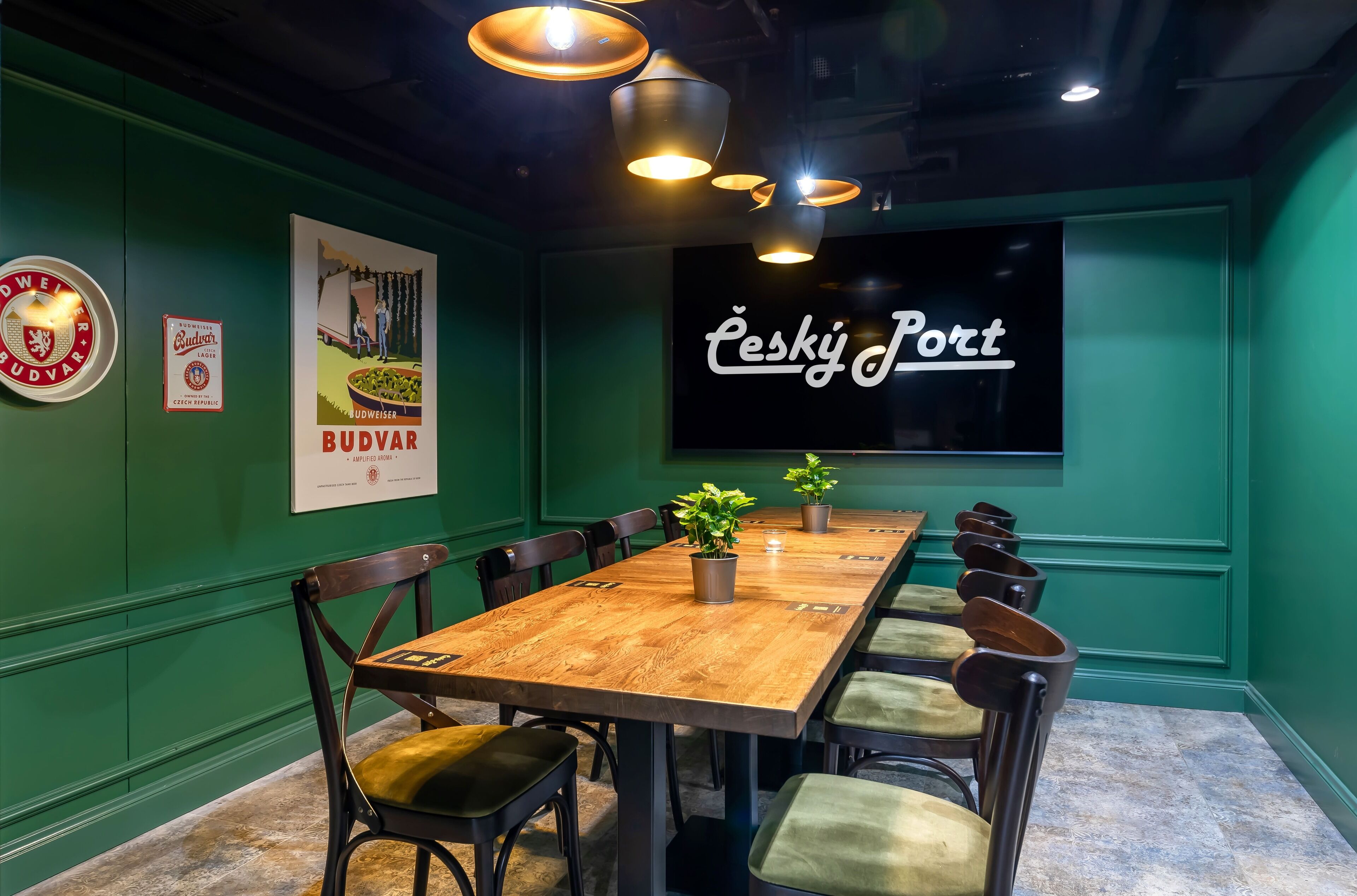 Une salle de conférence avec une table en bois, des murs verts et un grand écran affichant le texte « Cesky Port ».