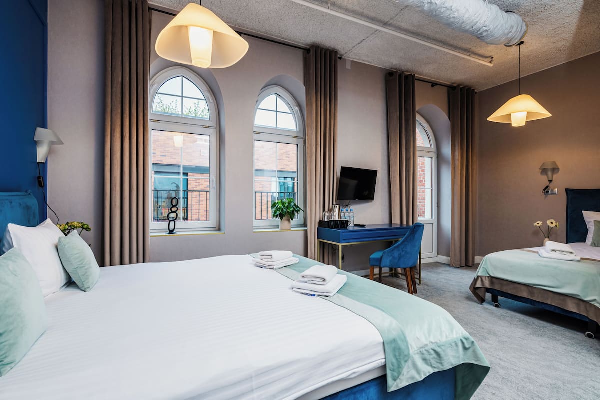 A hotel room with a large bed, a desk, and a TV.