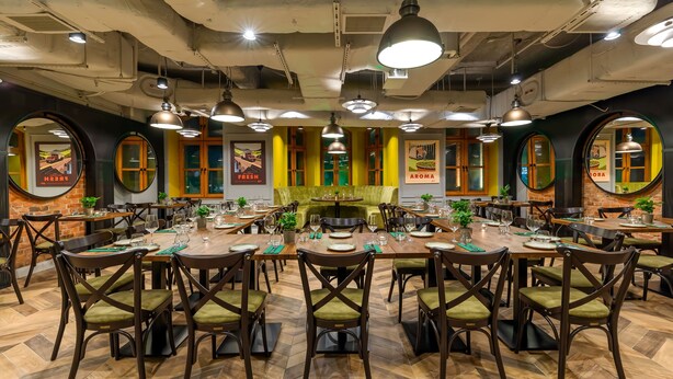Un restaurante con varias mesas, sillas e iluminación colgante.