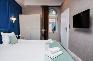 A hotel room with a bed, a wardrobe, a TV, and a window with curtains.