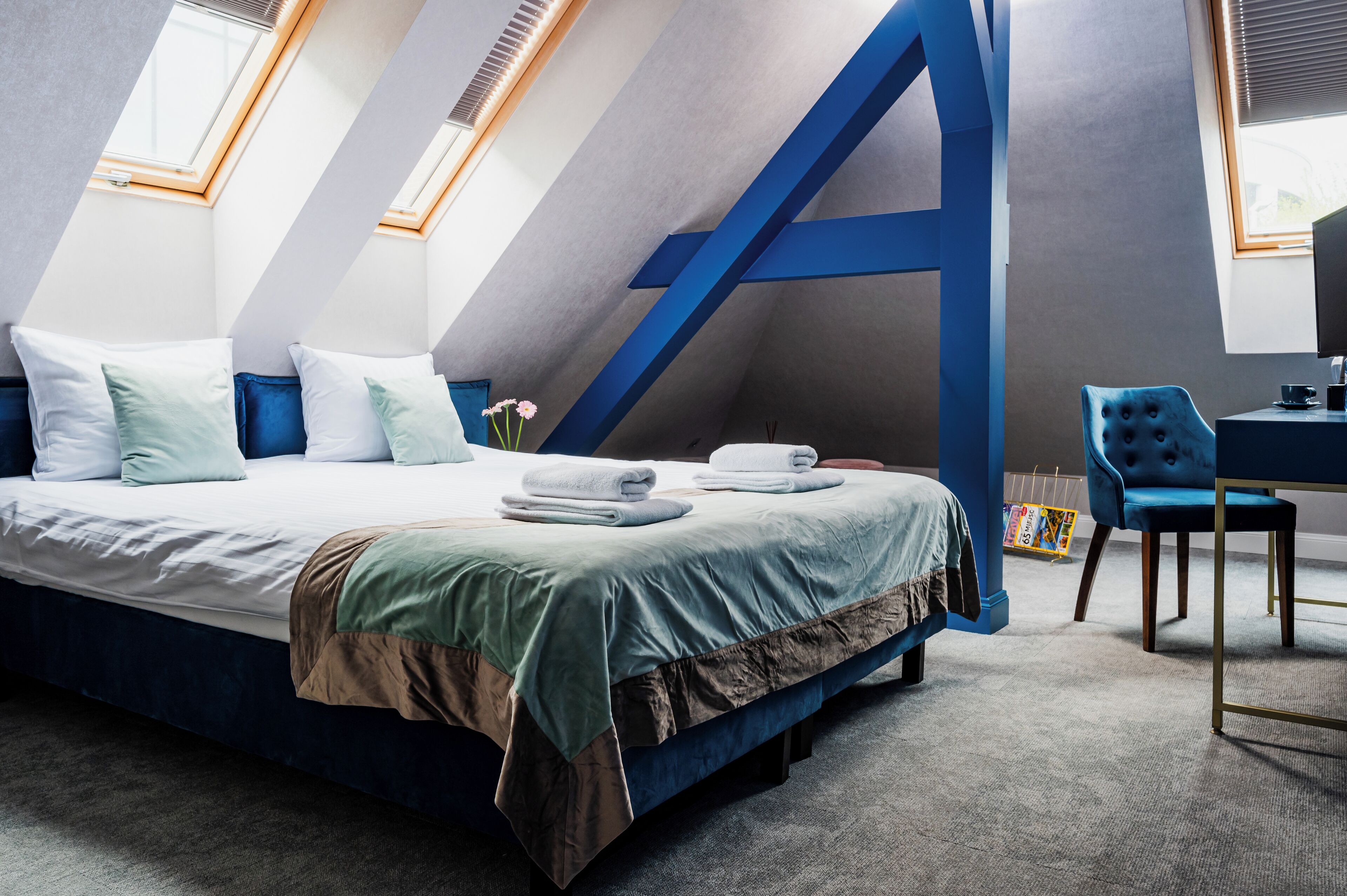 A modern bedroom with a large bed, a desk, and a chair.