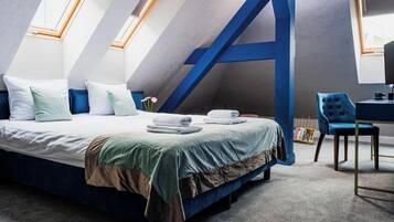 A modern bedroom with a large bed, a desk, and a chair.