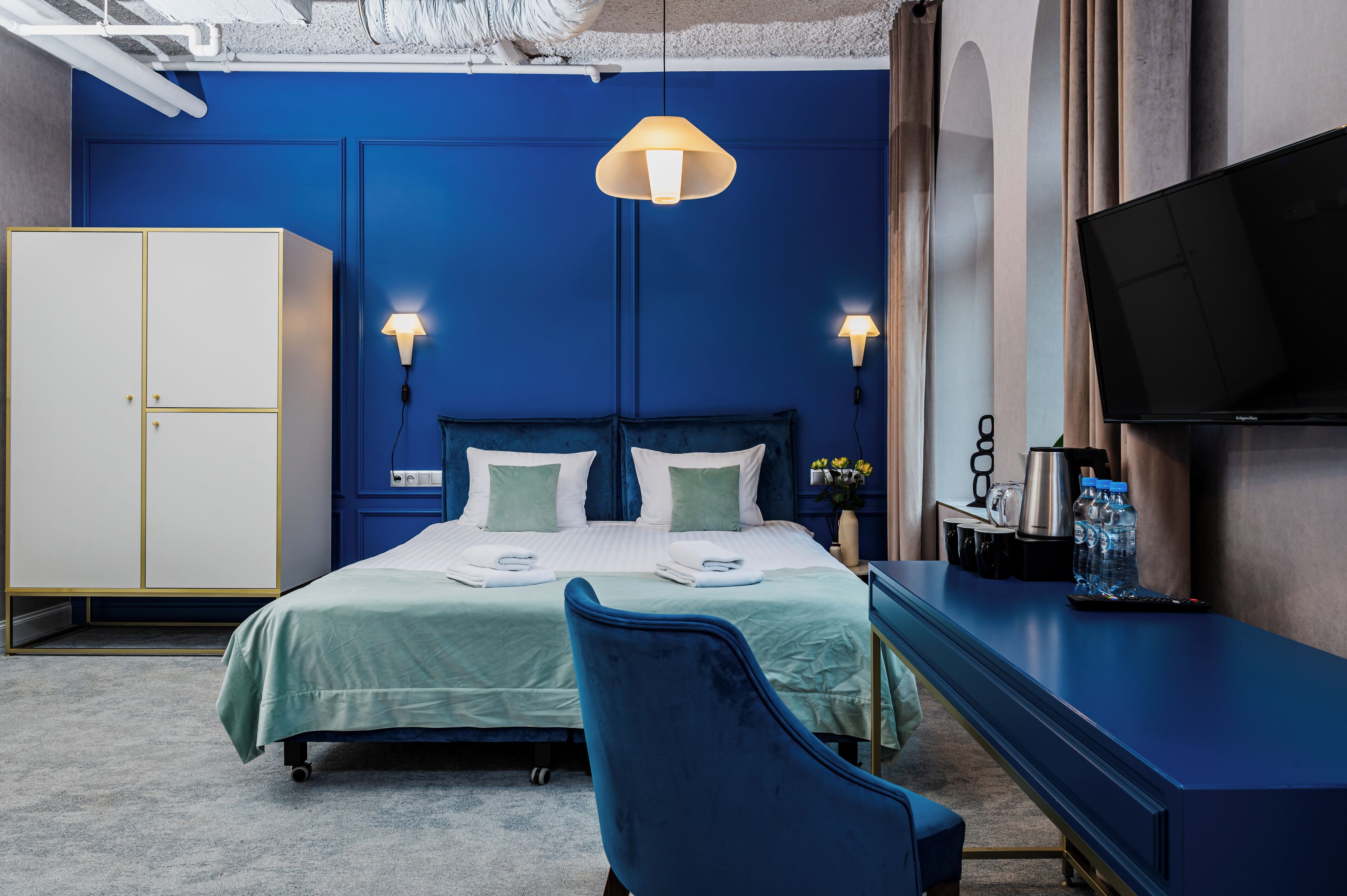 A hotel room with a bed, a desk, a TV, and a wardrobe.