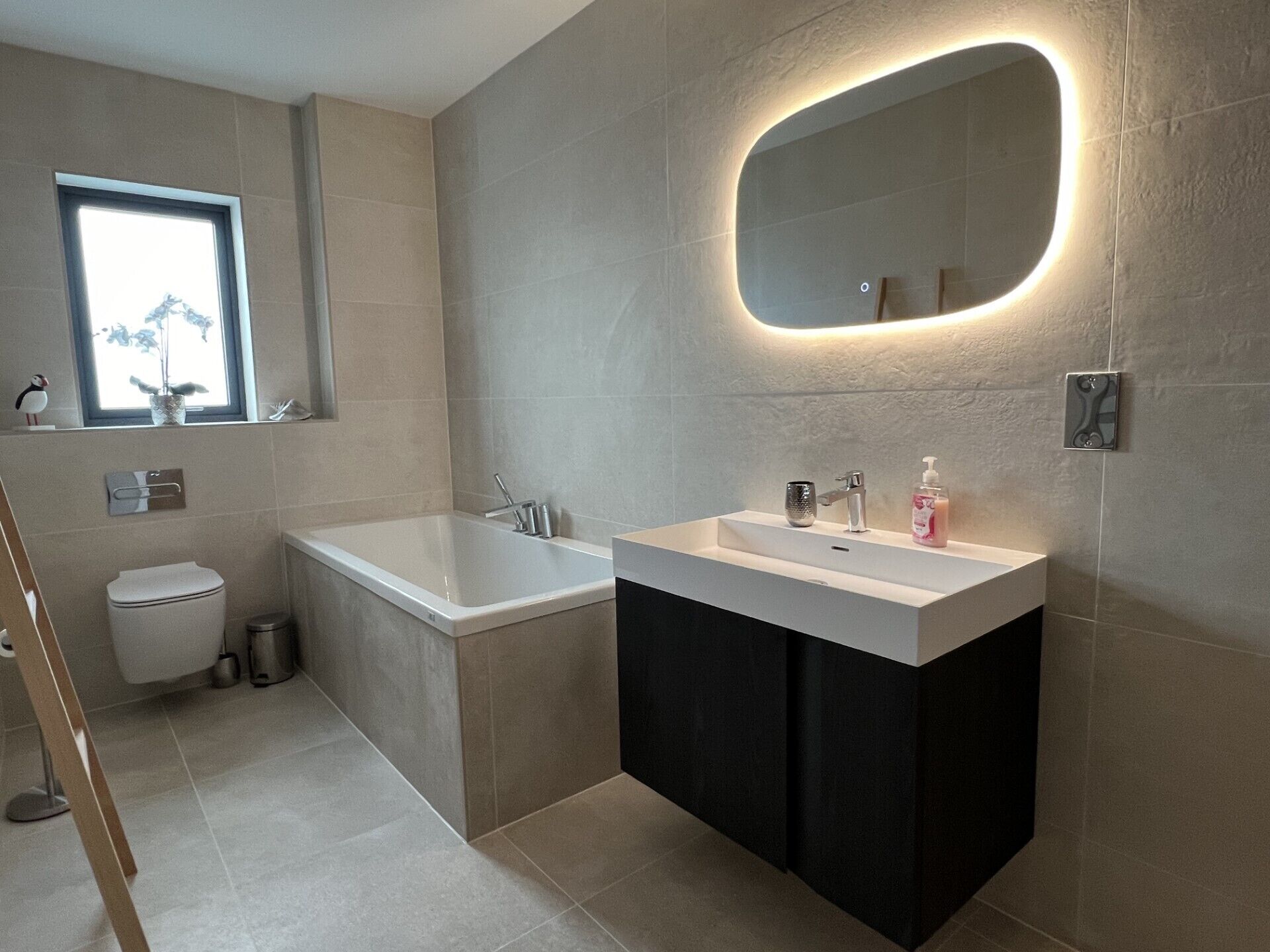 Een moderne badkamer met een bad, een wastafel en een toilet.