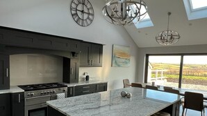 A modern kitchen with a large island, dark cabinetry, and a skylight. - Luxury Home in the heart of Cornwall's Seven Bays area, close to Padstow  (PADSTOW)