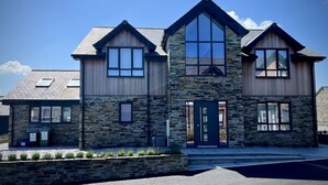 A two-story stone house with a gabled roof, large windows, and a front door. - Luxury Home in the heart of Cornwall's Seven Bays area, close to Padstow  (PADSTOW)