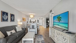 Un salon moderne avec un canapé gris, une table basse et un téléviseur posé sur un meuble en bois.