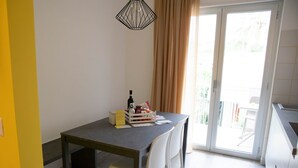 Zona pranzo con tavolo, sedie, una bottiglia e un cesto di oggetti sul tavolo.