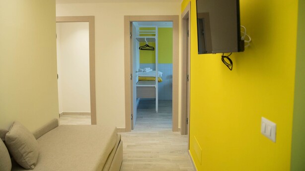 Camera d'albergo con un letto, una televisione e un corridoio che porta a un bagno con porta asciugamani.