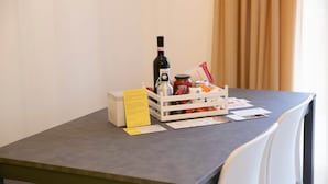 Un tavolo con una bottiglia di vino, una cassa bianca piena di snack e un biglietto giallo.