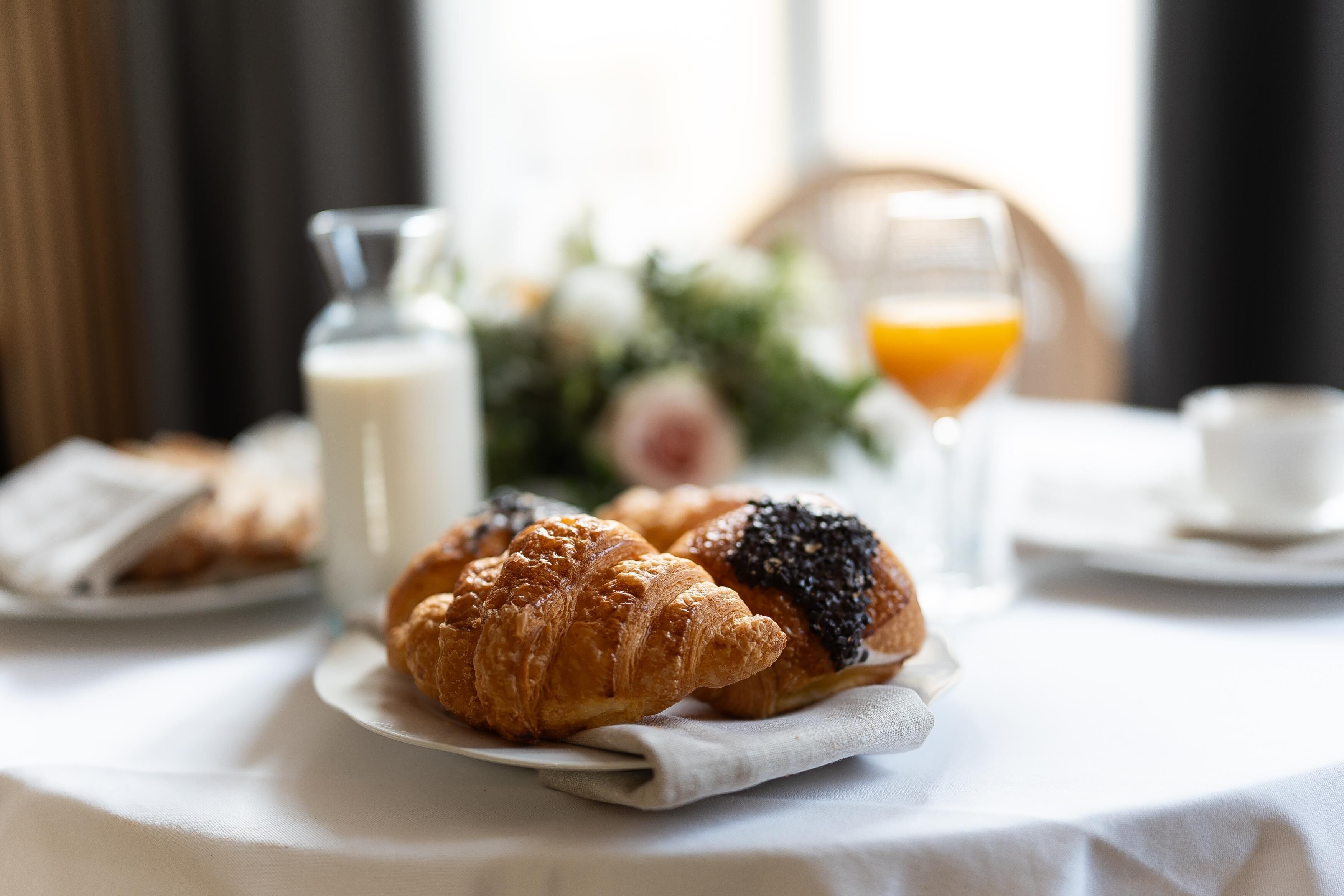 A breakfast setting with croissants and orange juice on a table.