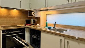 Cocina compacta con armarios blancos, pileta de acero inoxidable y horno empotrado.