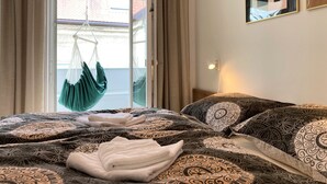 Un dormitorio con cama, una silla colgante y vistas al exterior.