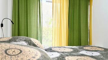 Una camera da letto con un letto, tende verdi e gialle, e biancheria da letto decorata.
