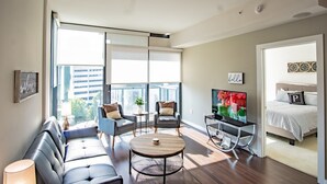 A modern living room with a sofa, two armchairs, a coffee table, a TV, and a bed with a letter 'P' pillow. - 3380 Peachtree Rd NE Atlanta, GA 30326, USA (Atlanta)