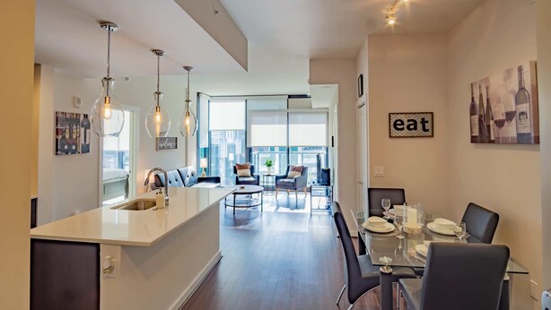 A modern kitchen with a central island, dining area with a glass table, and a living space with a sofa and chairs. - 3380 Peachtree Rd NE Atlanta, GA 30326, USA (Atlanta)