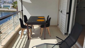 Un balcon avec une table et des chaises, un grand parasol et une vue sur la mer.