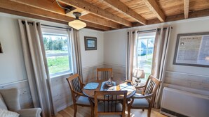 Un coin repas avec une table et des chaises en bois, un ventilateur de plafond et une fenêtre avec des rideaux.